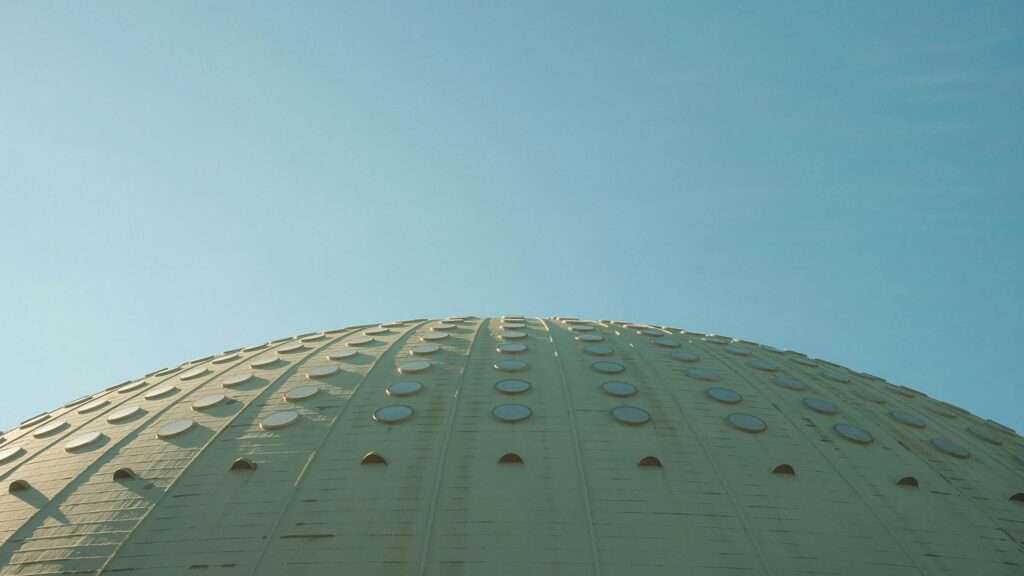 A modern architectural dome with circular patterns under a clear blue sky, showcasing abstract design.