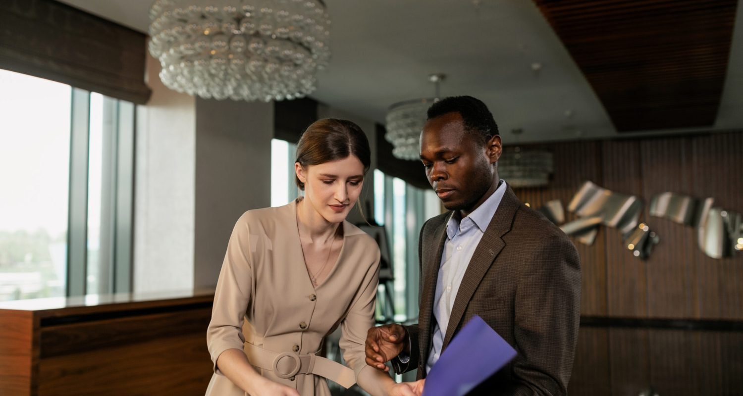 Two professionals reviewing documents during a business meeting in a modern office setting.